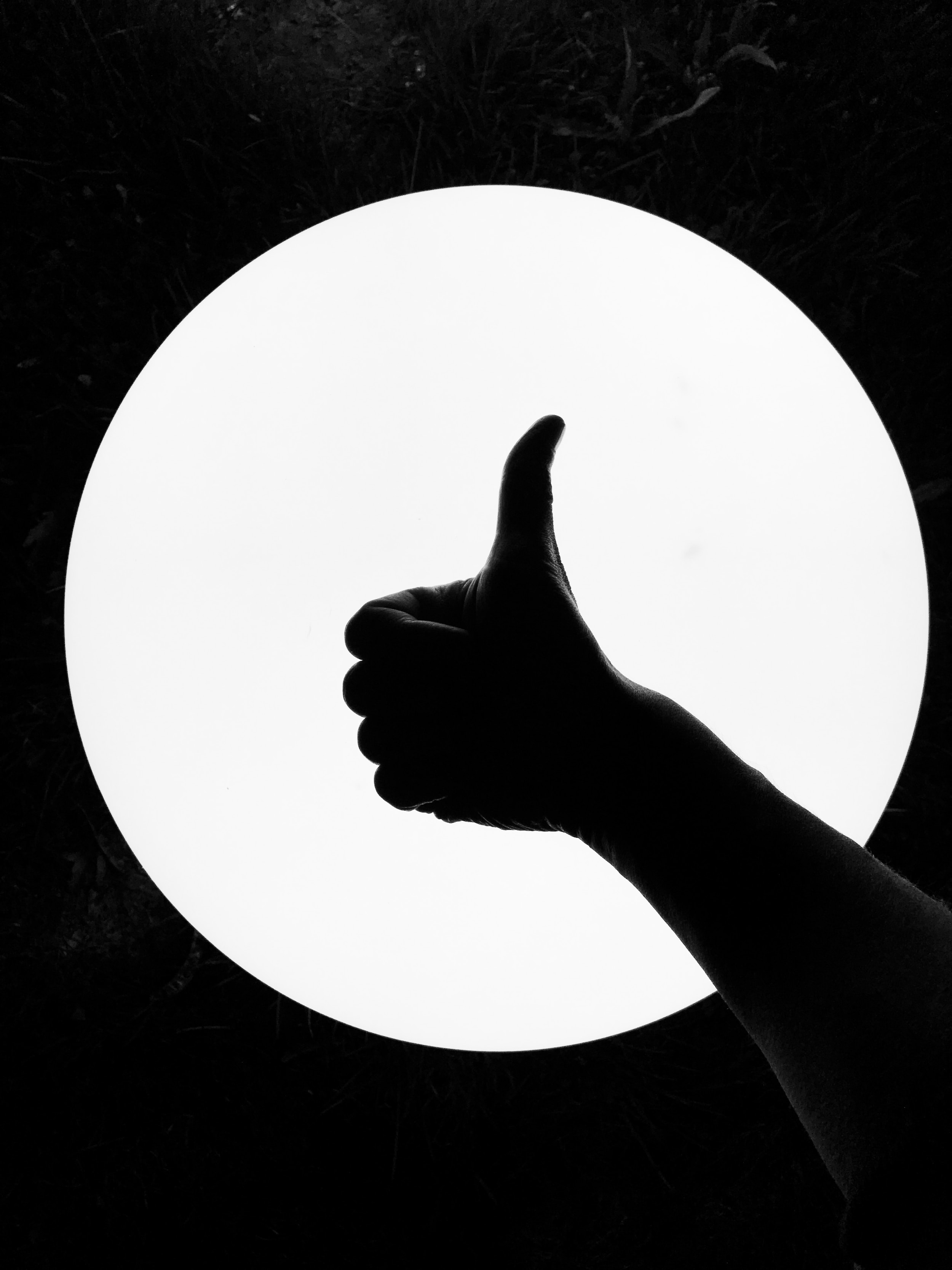 A silhouette of a hand giving the thumbs up gesture.