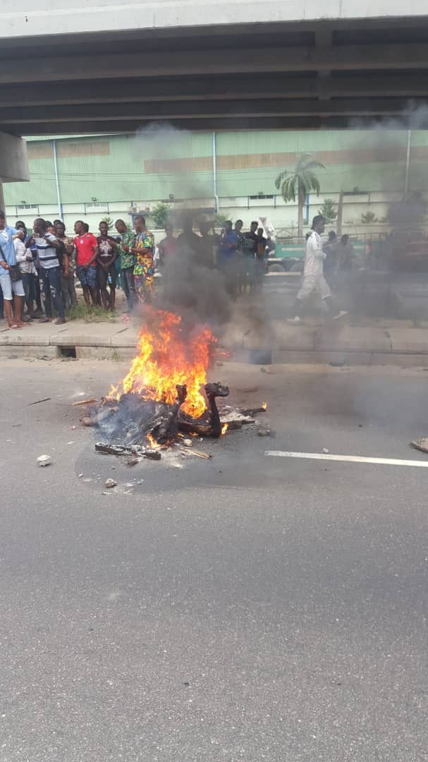 Graphic photos: Armed robber set ablaze after shooting lady dead outside a bank in Lagos