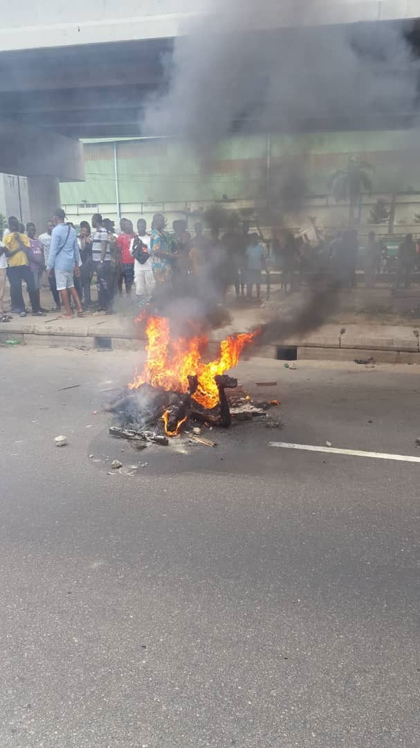 Graphic photos: Armed robber set ablaze after shooting lady dead outside a bank in Lagos