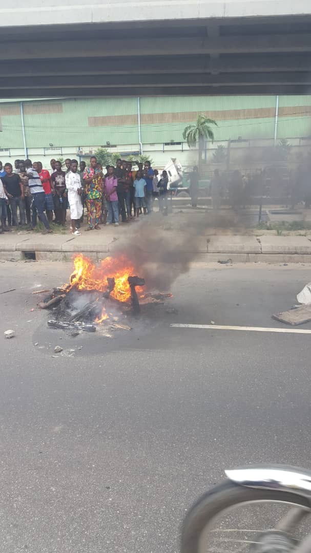 Graphic photos: Armed robber set ablaze after shooting lady dead outside a bank in Lagos