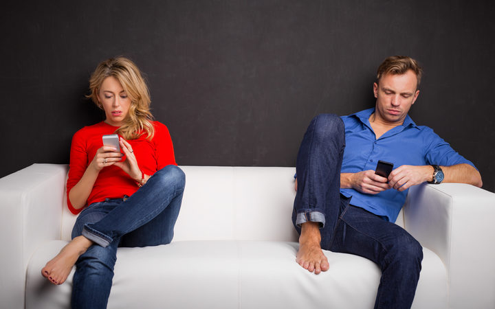 couple on couch each on phones