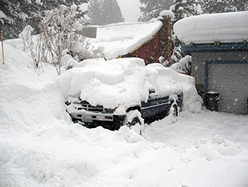 a photo of several feet of snow burying a pickup truck, a house and a garage