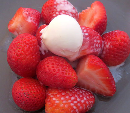 A scoop of hot ice cream served on strawberries.