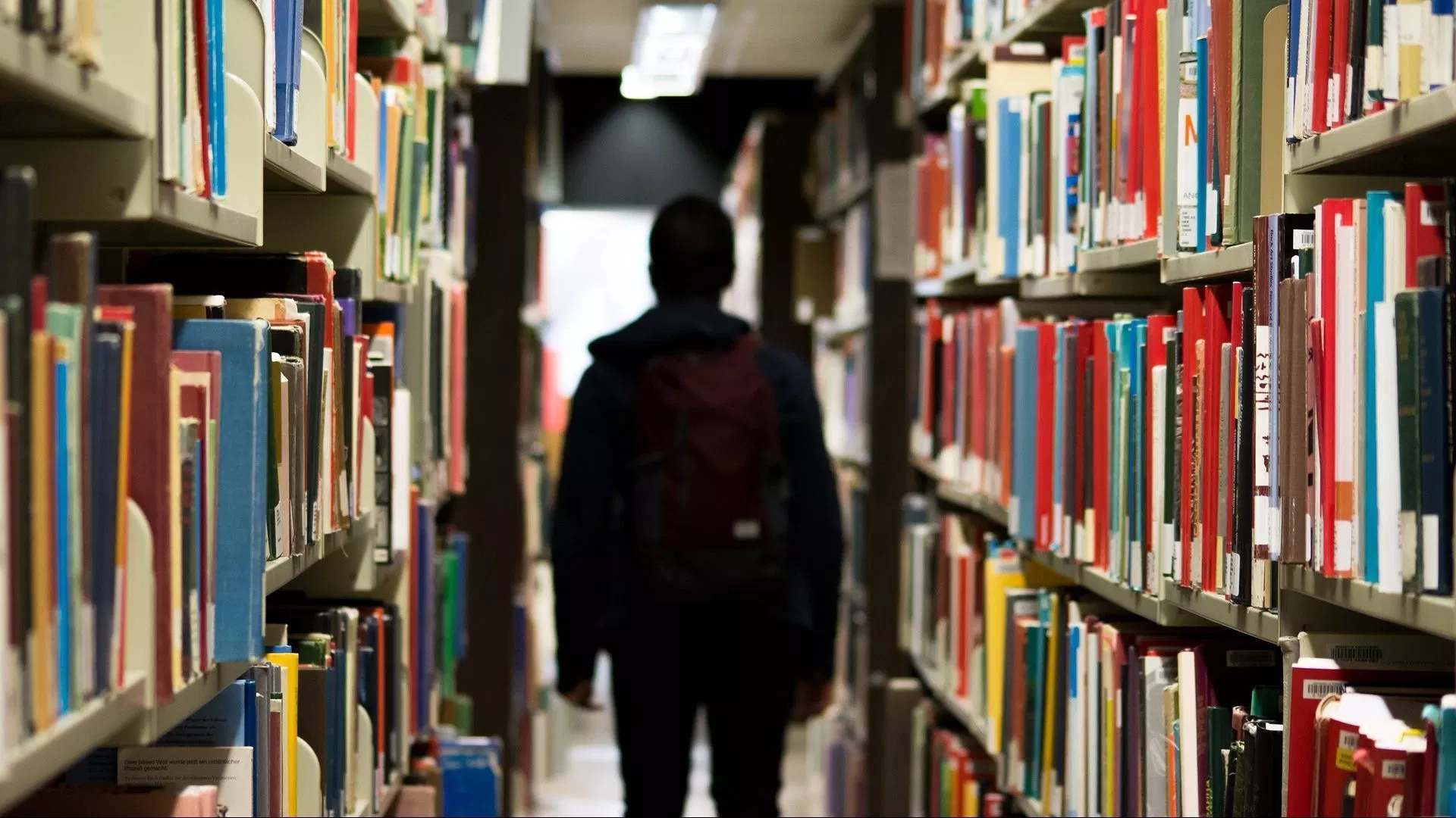 Image: Person walking through library shelves