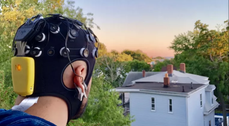 Image: A man wearing the headset and staring out into the distance at a sunset