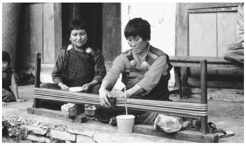 A Bhutanese woman weaving alongside a street. The majority of commercial production activity involves cottage industries.