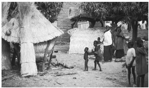 People stand by huts in a Bobo village in Burkina Faso. The majority of citizens, about 90 percent, live in rural areas, among Burkina Faso's 8000 villages.