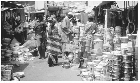 Traditional household equipment stands on sale next to modern Western items in a market in Bobo-Diolasso.