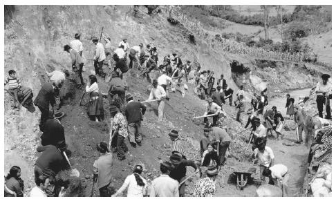 Villagers of all ages dig through a hill to build a road in rural Colombia.