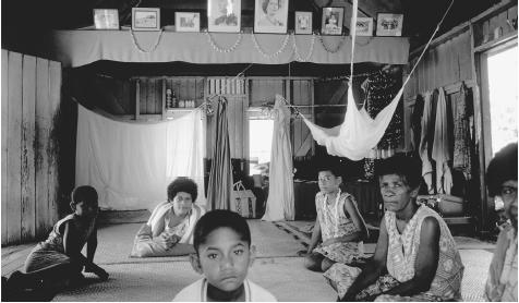 A family inside their house in Shell Village, Fiji. Traditional families might include unmarried children, married sons and their families, an elderly widowed parent, and the sister of the head of the household.