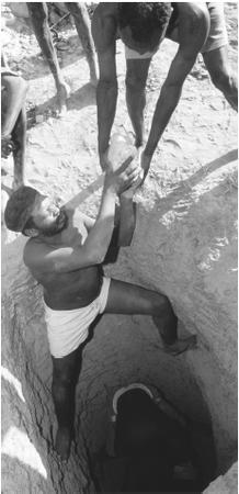 Turkana men working at a gold mine in northern Kenya pass blocks of gold-bearing ore to the surface of a shaft. The mines often lie sixty or so feet below the ground.