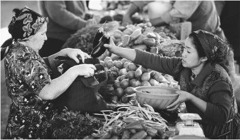 A produce vendor places eggplants in a customer's bag at the Osh Market. Bishkek, Kyrgyzstan.