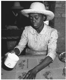 A woman decorates a large sheet of paper with pressed flowers. The paper industry plays a significant role in the nation's economy.