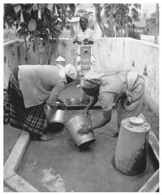 Women collecting water. While men commonly dress in a Western style, women tend to wear chitenjes, large pieces of colorful fabric.