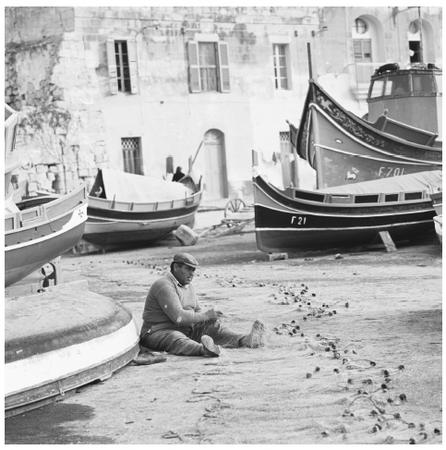 A fisherman mending a net in the village of Marsa Xlokk. The Mediterranean Sea surrounds Malta.