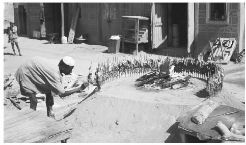 A man places skewers of meat in a circle around a fire. Rural Nigerians favor traditional foods and preparation techniques.