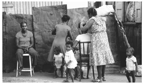 Two women cut hair outside a house on Saint Kitts Island.