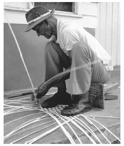 An elderly man weaves a fish trap from dried palm fronds. Fishing is still considered only a man's profession.