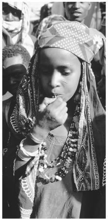 A Fulani woman eats at a market. Food is a large part of many social interactions.