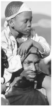 A boy sits on his father's shoulders during a Carnival procession. Carnival is a major celebration.