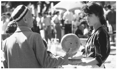 A vendor sells round loaves of bread called tandirnon to a customer at the Bibi Bazaar in Samarkand. Bread is especially important in Uzbek culture.