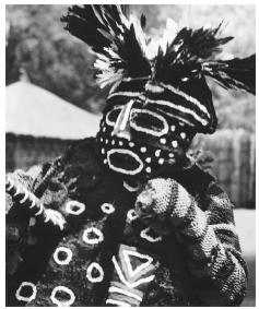 A woman wears a mask made of bark fibers, in preparation for an initation ceremony, Zambia.