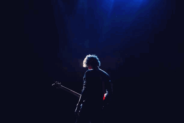 rear view of man with guitar standing in darkroom - musicien photos et images de collection