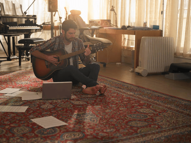 a man playing guitar next to a laptop - musicien photos et images de collection