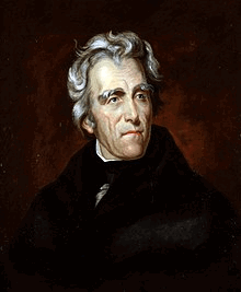 A man with wavy gray hair in white shirt, black bowtie, and black coat. Faces left.