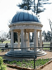 A tomb in a garden covered by a circular roof