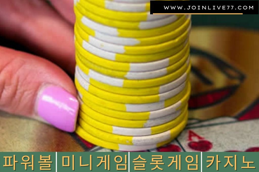 Yellow casino chip hold by a hand with pink nails.