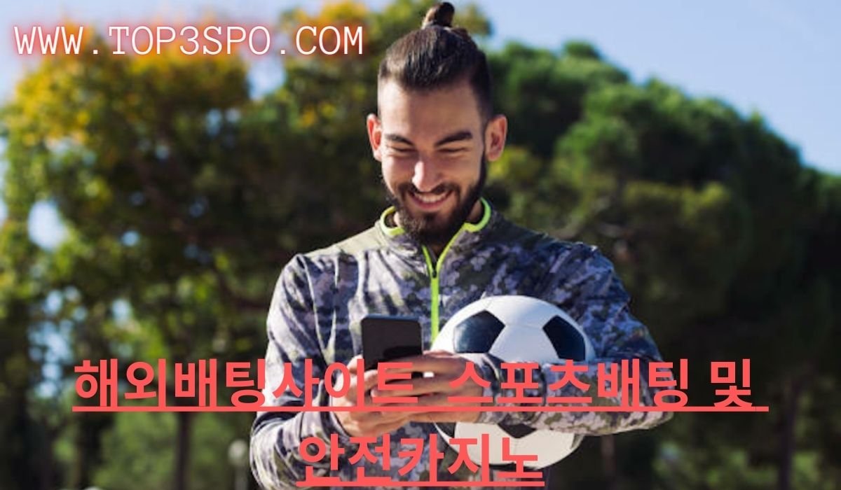 sports bettor smiling at his phone and holding a foot ball 