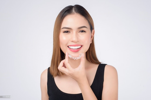 Girl holding Invisalign in her hand and smiling 