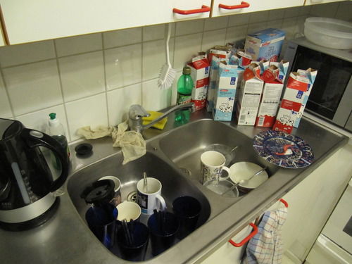 Kahvikupeista täyttyvä tiskiallas, paljon maitotölkkejö
